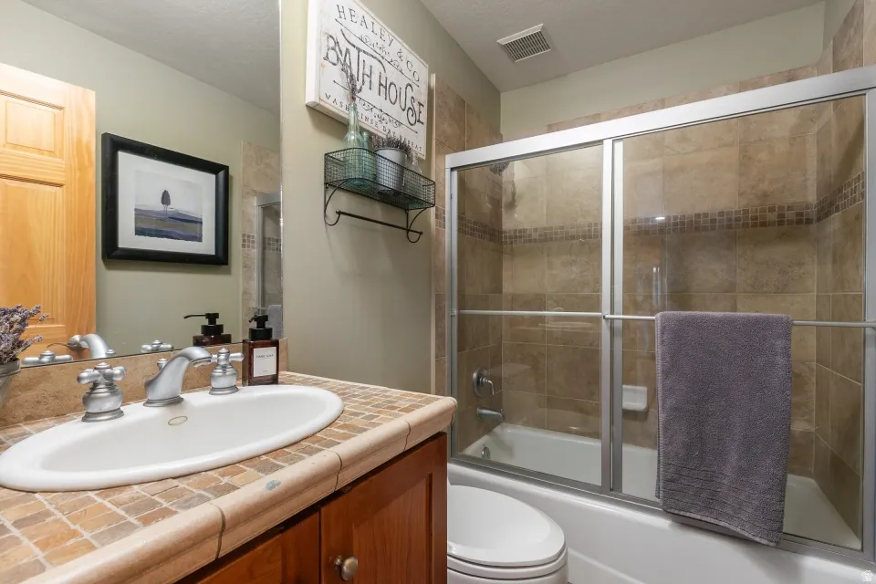 Built-in vanity with a tiled countertop and oval basin sink