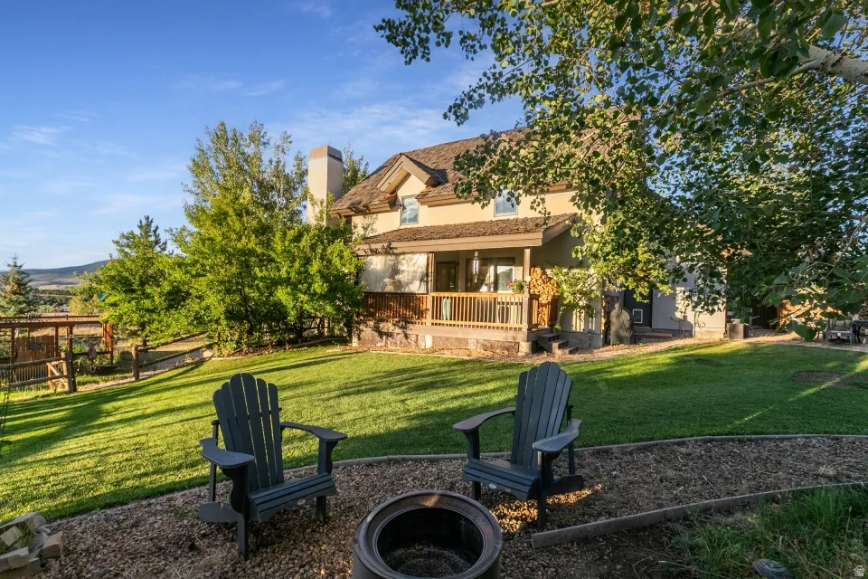 Expansive lawn with a fire pit, bordered by mature trees and a wooden fence