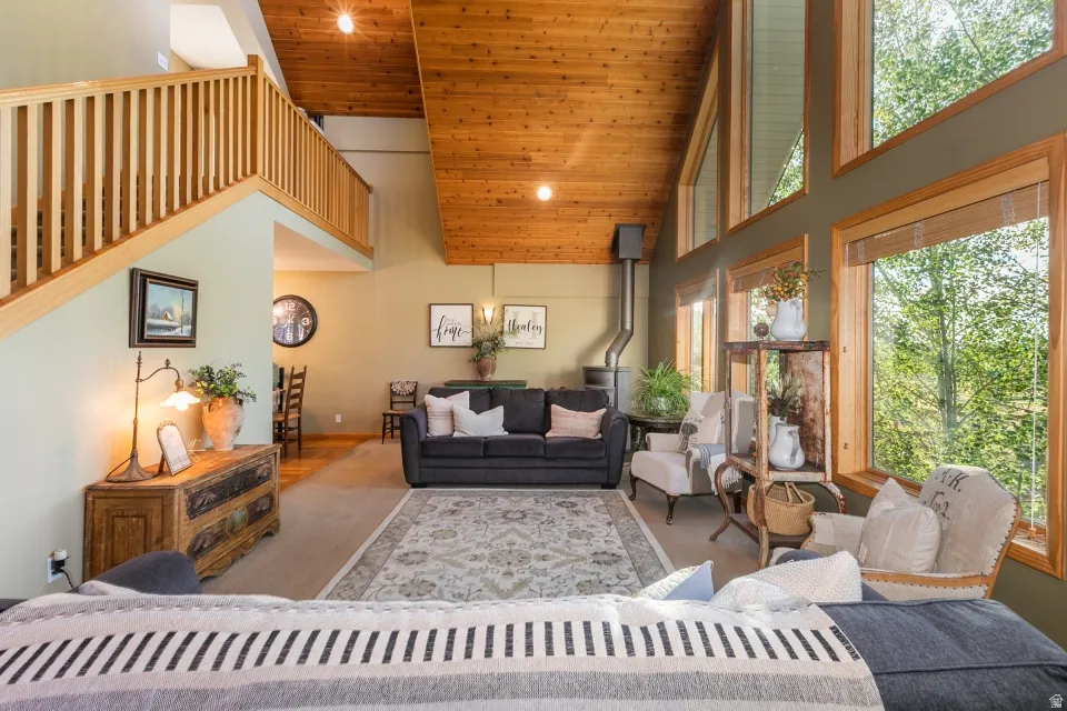 Vaulted wood-finish ceiling, large picture windows, wood-finish flooring, built-in wood-burning stove, and a wood staircase