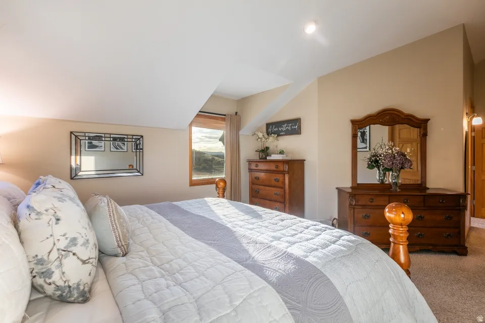 Sloped ceiling design with recessed lighting, wall-mounted mirror, and wood-framed window