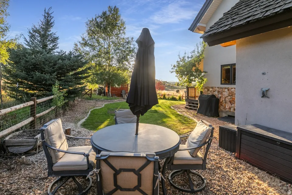 Expansive backyard with a manicured lawn, established evergreens, and a decorative wood fence