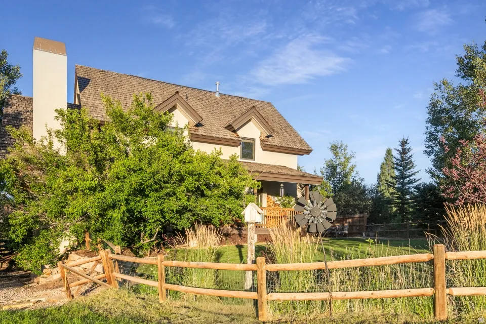 Stucco exterior with a prominent chimney, dormer windows, and a covered front porch