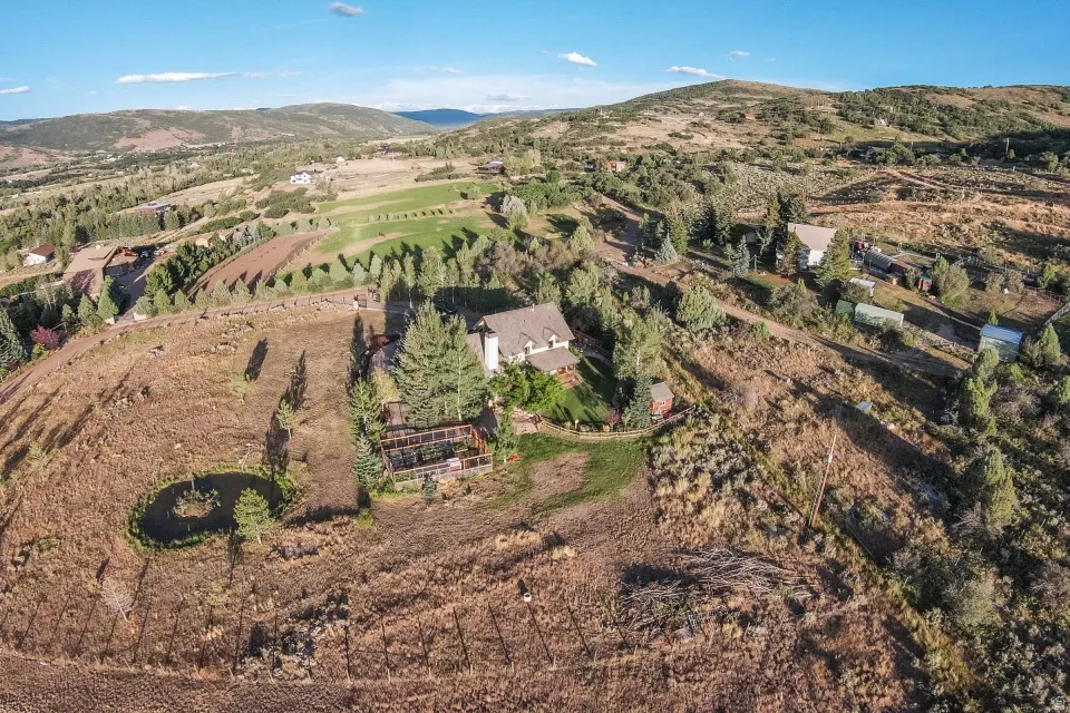 Expansive property featuring a central residence, surrounding natural landscaping, and a water feature