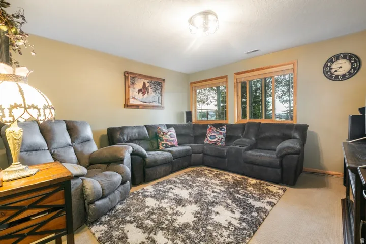 Recessed ceiling light fixture, two windows with wood trim, wall-mounted clock, and carpet flooring