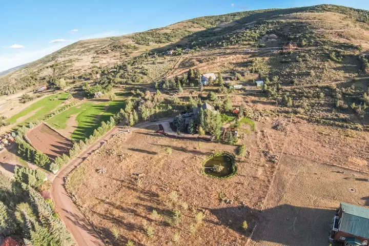 Expansive natural landscape featuring a private pond, mature trees, and a distant mountainous backdrop