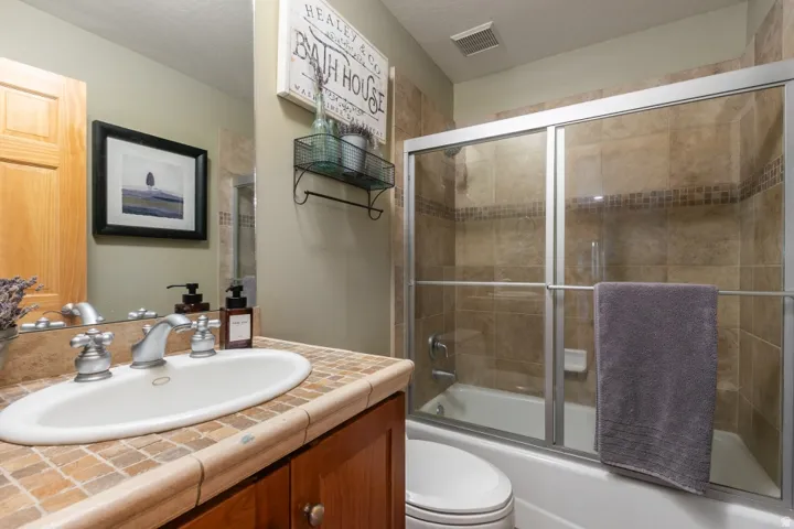 Built-in vanity with a tiled countertop and oval basin sink