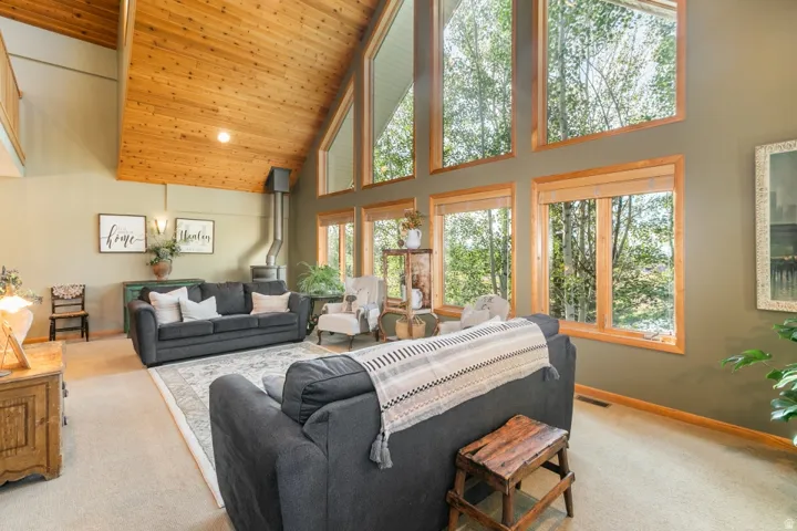 Vaulted wood-finish ceiling, expansive windows with wood trim, and a built-in wood stove
