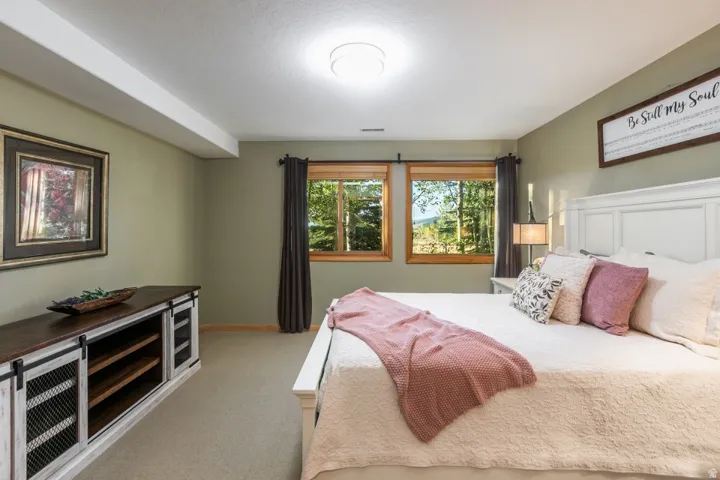 Carpeted room featuring two windows with wood frames, a built-in entertainment console with sliding barn door style fronts, and a recessed ceiling light fixture
