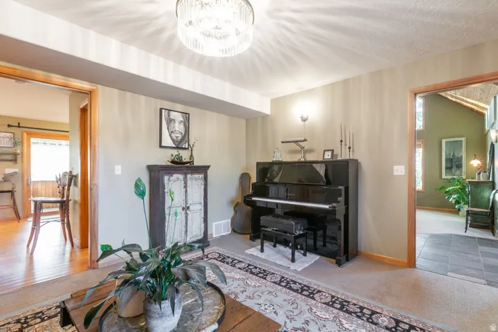 Recessed ceiling with an ornamental chandelier, wall sconce lighting, and a neutral wall color