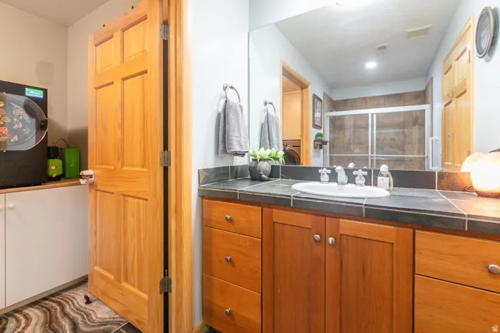Vanity with an integrated sink, tile countertop, and wood-finish cabinetry