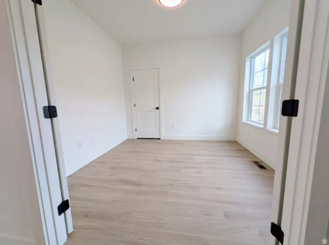 Bright interior space featuring wood-finish flooring, white walls, and multiple windows