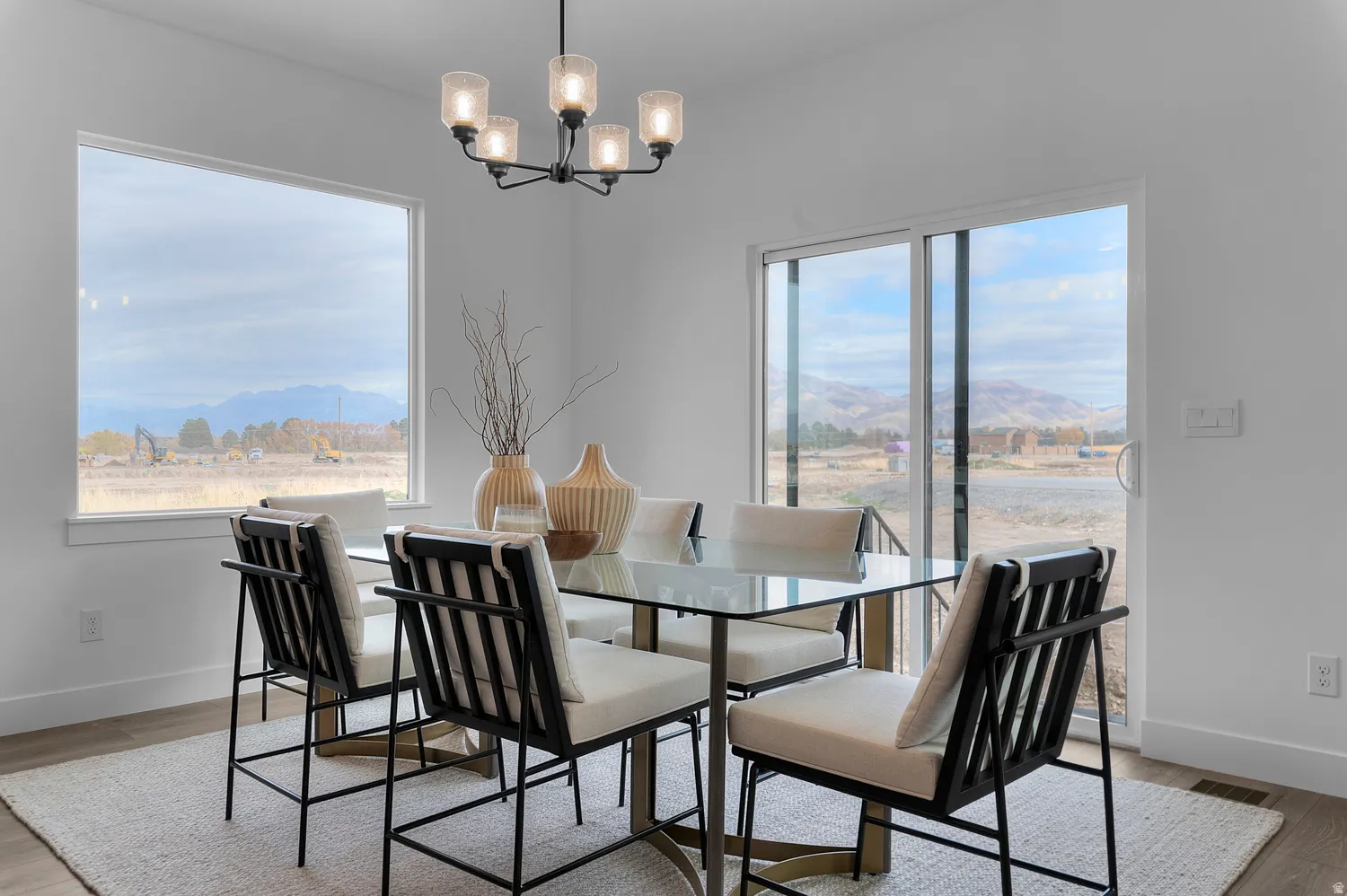 Expansive windows, sliding glass door, contemporary chandelier, and light wood-finish flooring