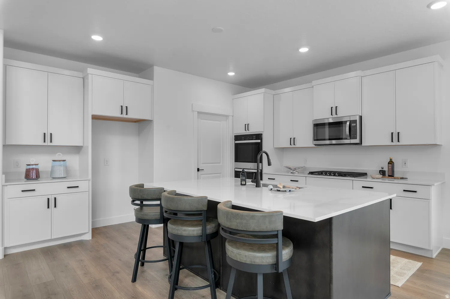 Modern kitchen featuring white cabinetry, stainless steel appliances, a center island with a light-colored countertop, and recessed lighting