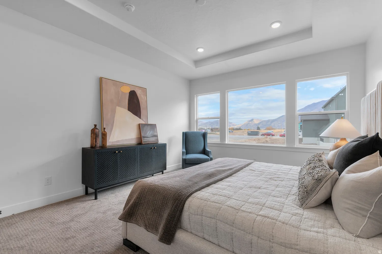 Tray ceiling with recessed lighting, large windows, and carpeted flooring
