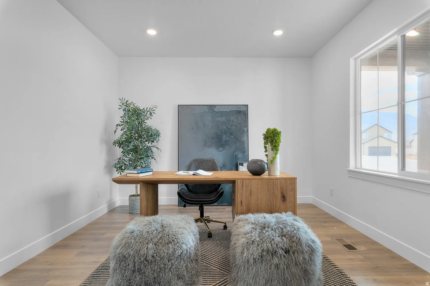 Recessed lighting illuminates a room featuring wood-finish flooring and a large window