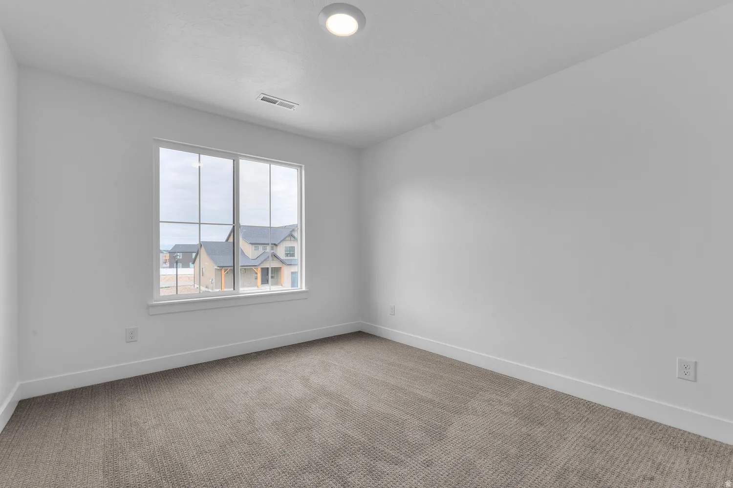 Neutral carpet flooring, recessed ceiling light, and a large window with white trim