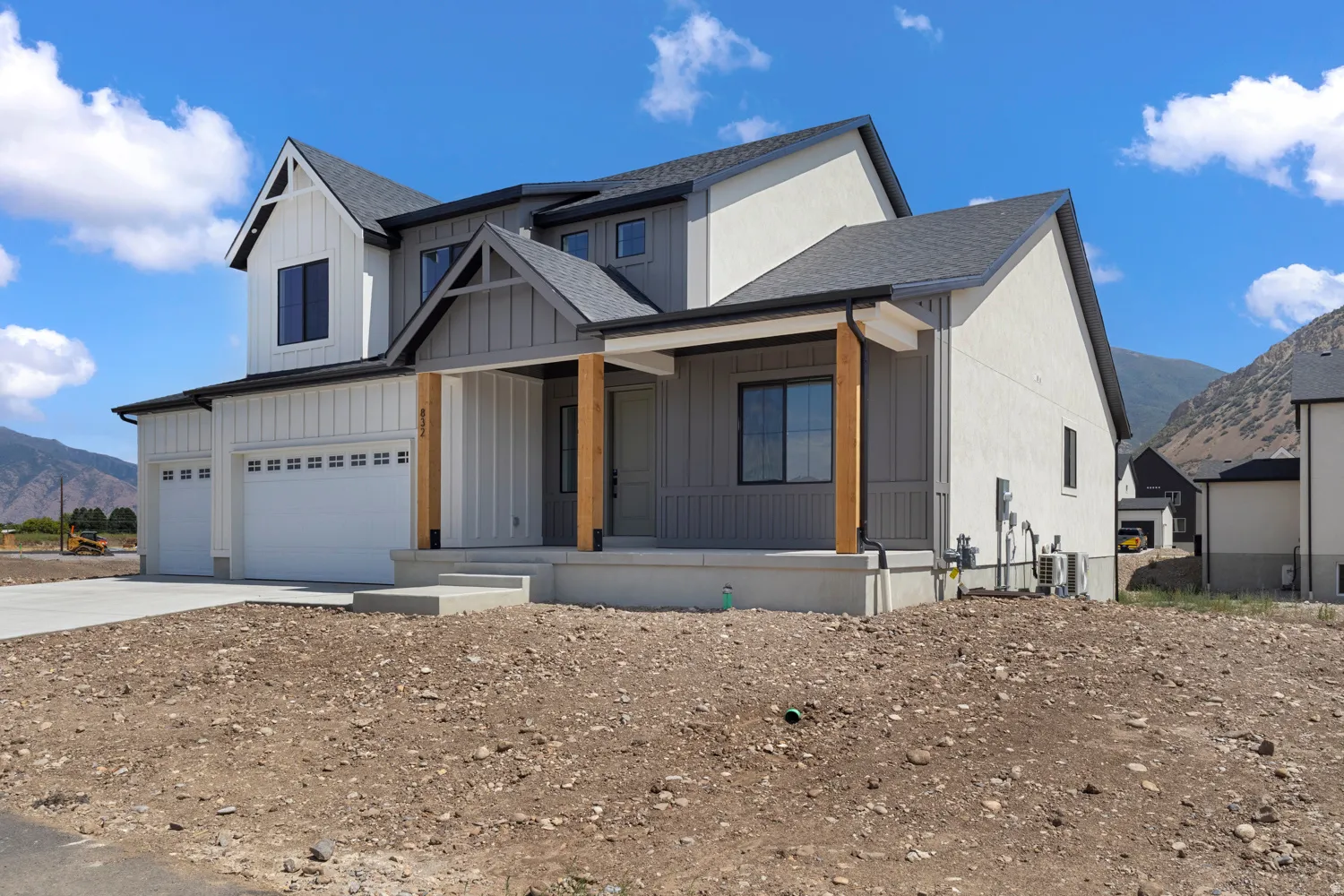 Contemporary two-story exterior with board and batten siding, attached two-car garage, covered porch with natural wood columns, and dark-framed windows