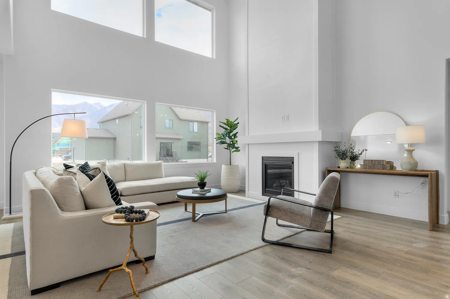 Vaulted ceilings with upper transom windows, a floor-to-ceiling fireplace with a black insert, and wood-finish flooring