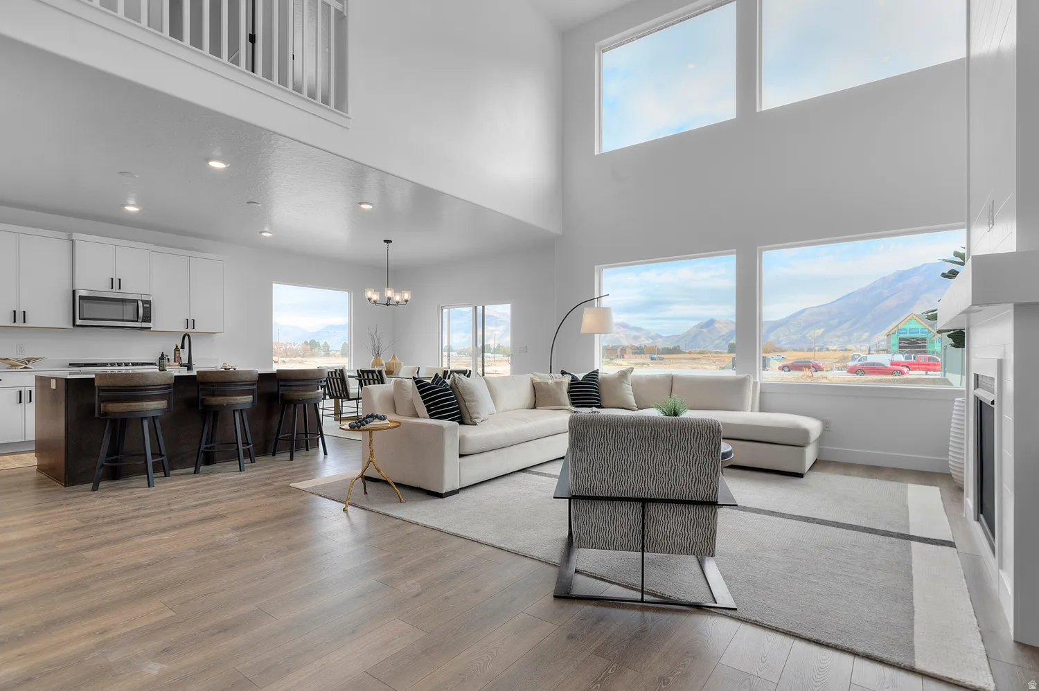 Open-concept living space featuring high ceilings, wood-finish flooring, a contemporary fireplace, and a kitchen island with seating