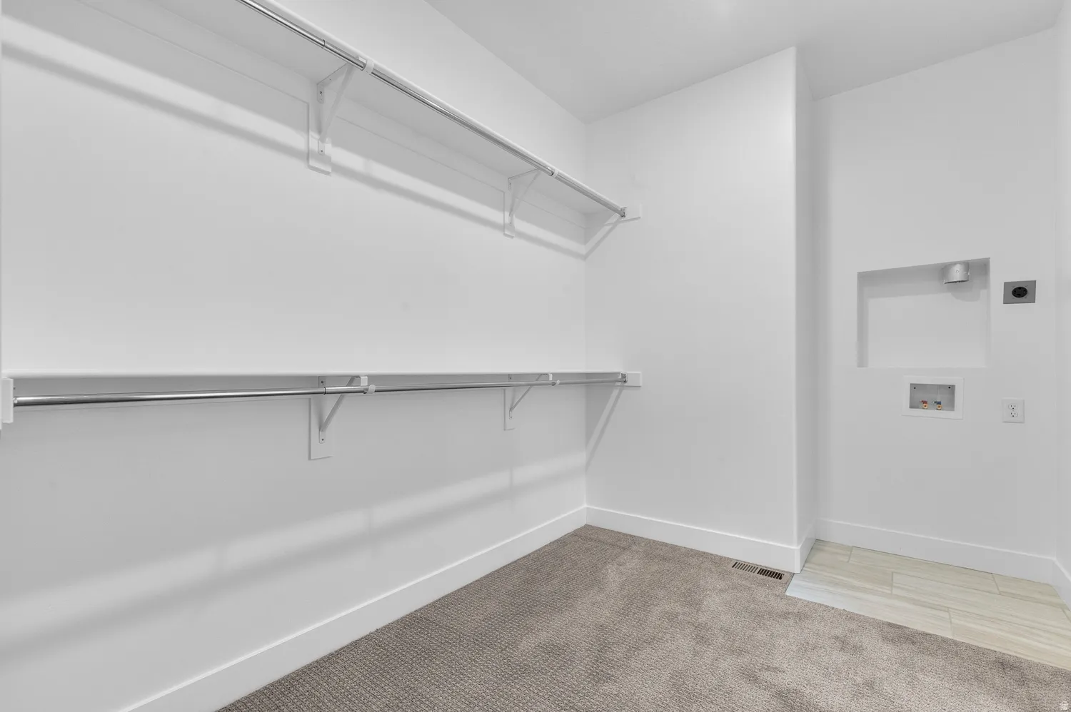 Built-in shelving and hanging rods, plush carpet flooring, recessed lighting, and a dedicated laundry area with tile flooring