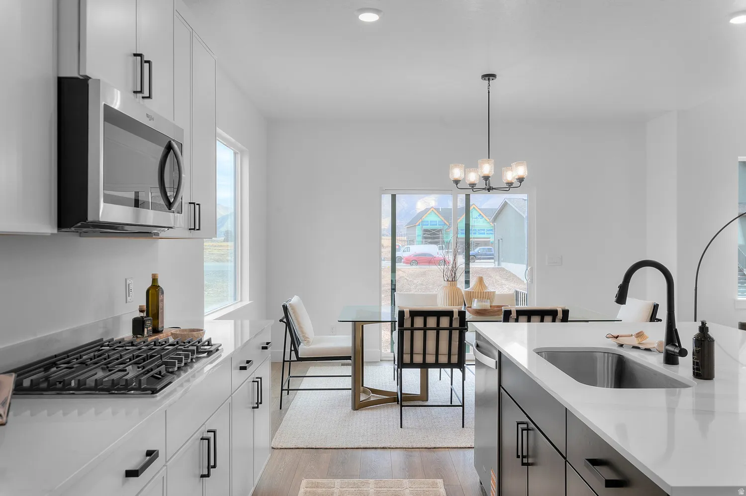 Kitchen featuring stainless steel appliances, white cabinetry with dark hardware, a gas range, and a kitchen island with an undermount sink and matte black faucet