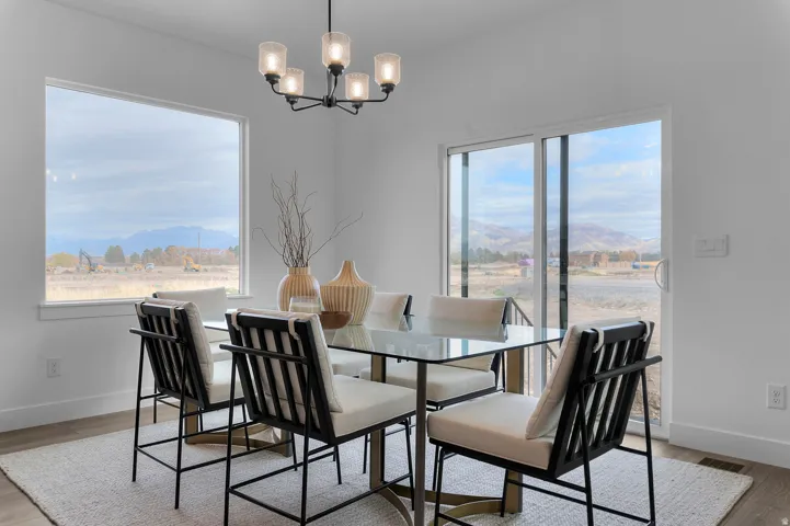 Expansive windows, sliding glass door, contemporary chandelier, and light wood-finish flooring