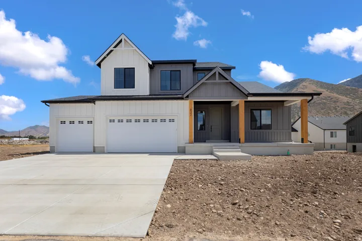 Modern farmhouse exterior with a covered entry, wood support columns, board and batten siding, and an attached two-car garage