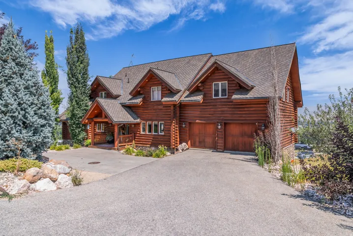 Log cabin style exterior with a gabled roofline, covered entry, and attached two-car garage