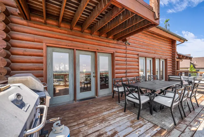 Expansive wood deck with exposed ceiling joists and log siding exterior