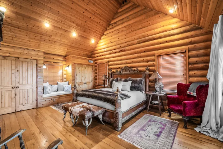 Vaulted wood-paneled ceiling, log-style wall construction, wood-finish flooring, built-in window bench, and wood double doors