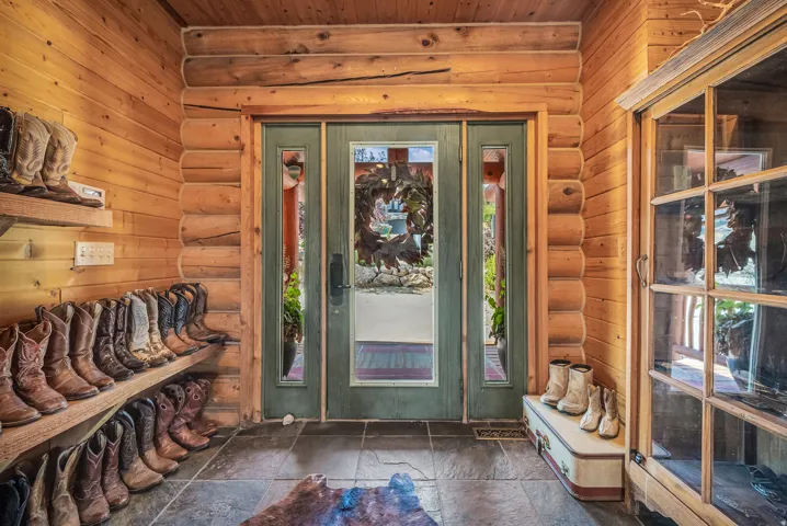 Rustic entryway featuring log walls, wood-paneled ceiling, slate tile flooring, and a double-door entry with integrated windows