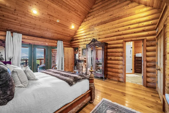 Vaulted wood-paneled ceiling, wood-plank flooring, log-cabin style walls, double exterior doors, and a wood framed interior door