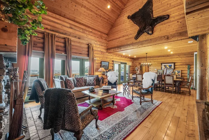 Vaulted wood-paneled ceiling, wood-finish flooring, stone-clad fireplace, and multiple glass doors