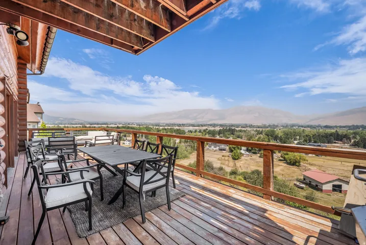 Expansive wood deck with a perimeter railing, offering an elevated perspective of the surrounding landscape and distant mountains