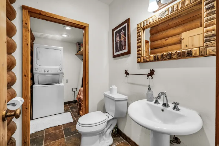 Pedestal sink with chrome fixtures, two-piece toilet, and wood-framed mirror
