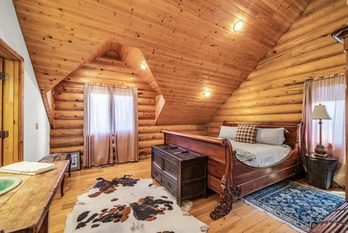 Wood-paneled sloped ceiling, log walls, and wood-finish flooring
