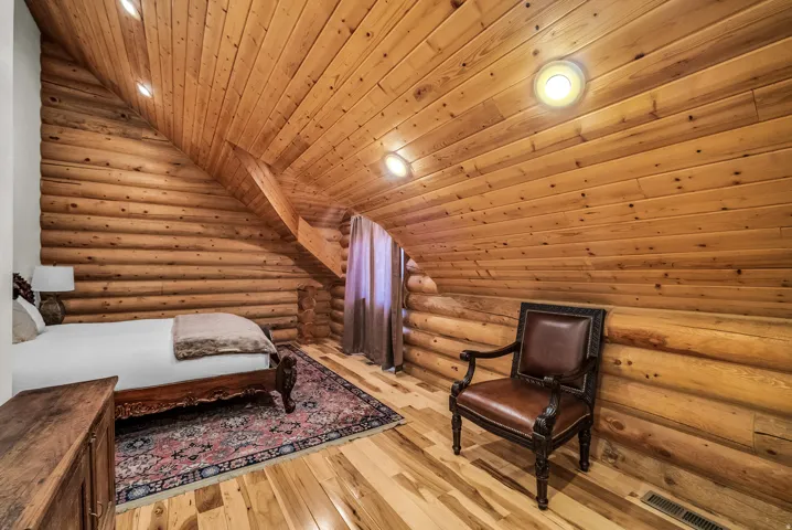 Sloped wood-paneled ceiling with recessed lighting, wood-plank walls, wood-finish flooring, and a window with drapes