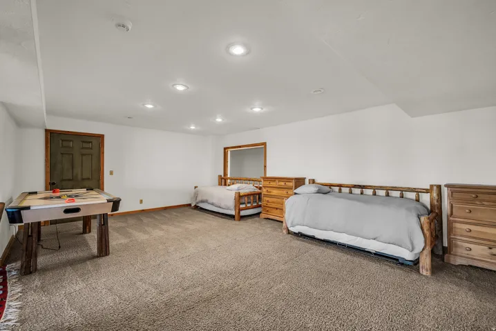 Carpeted room with recessed lighting, a paneled door, and wood-finish trim