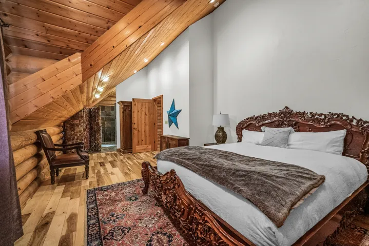 Wood-finish flooring, exposed wood beam ceiling, white walls, and built-in wood-paneled doors