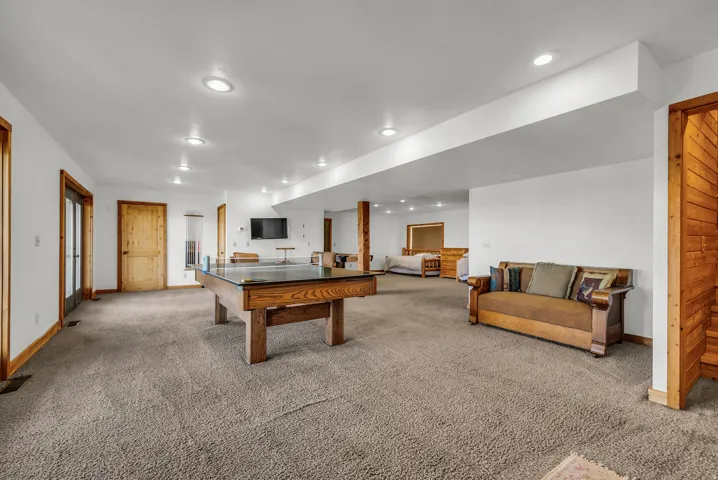 Open-concept living area with recessed lighting, light-colored carpeting, and light wood trim