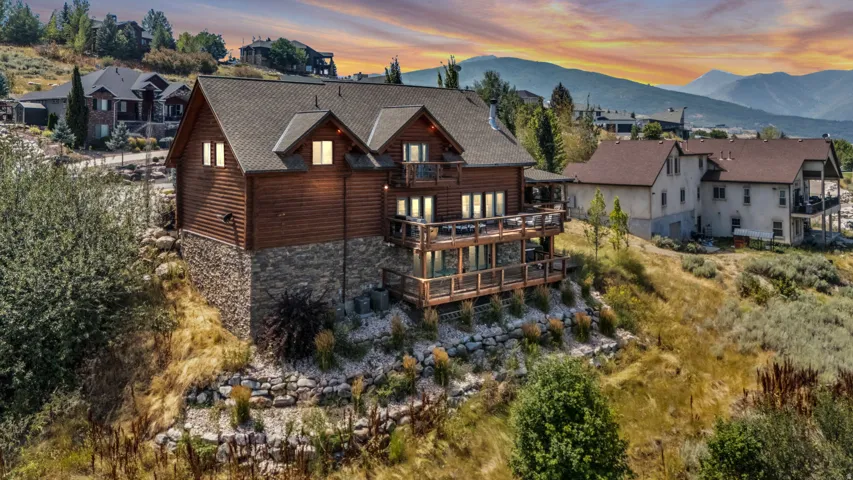 Hillside property featuring wood siding, stone foundation, multiple balconies, and a multi-level deck
