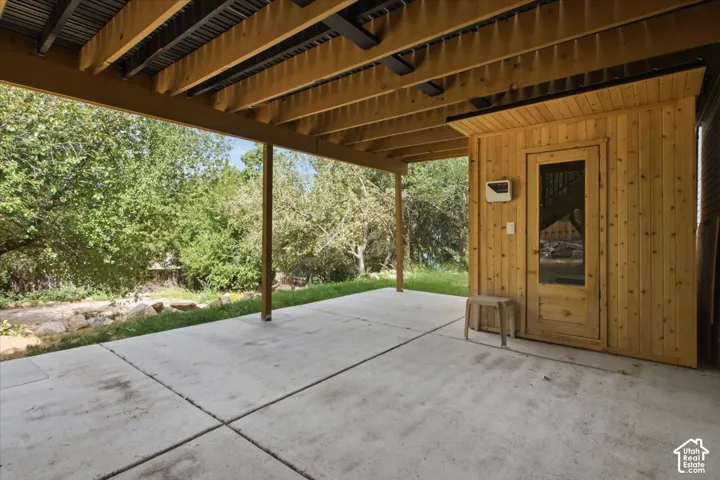 Covered concrete patio with exposed wood joists and a sauna