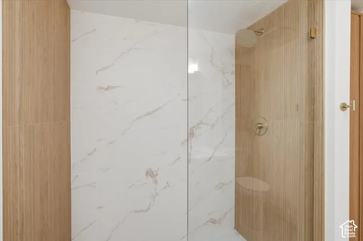 Enclosed shower with clear glass panel, large format marble tiles and a rainfall showerhead