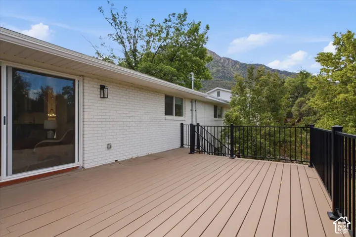 Expansive outdoor deck featuring wood-finish composite decking, black metal railing, and a sliding glass door