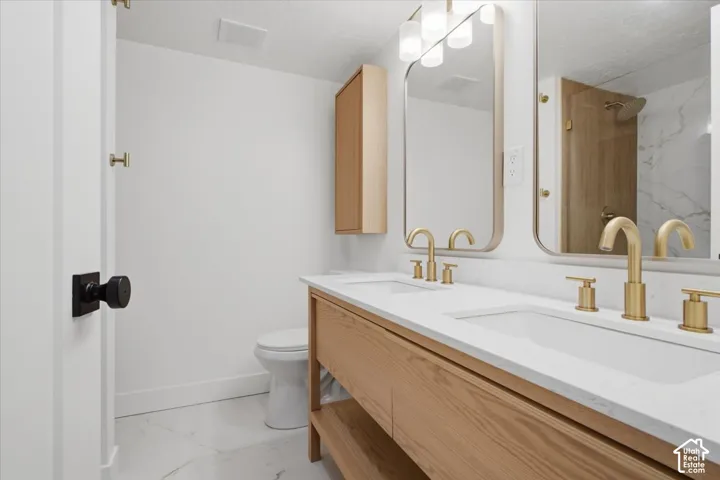 Main bedroom vanity with dual sinks, quartz countertops, and gold-tone fixtures