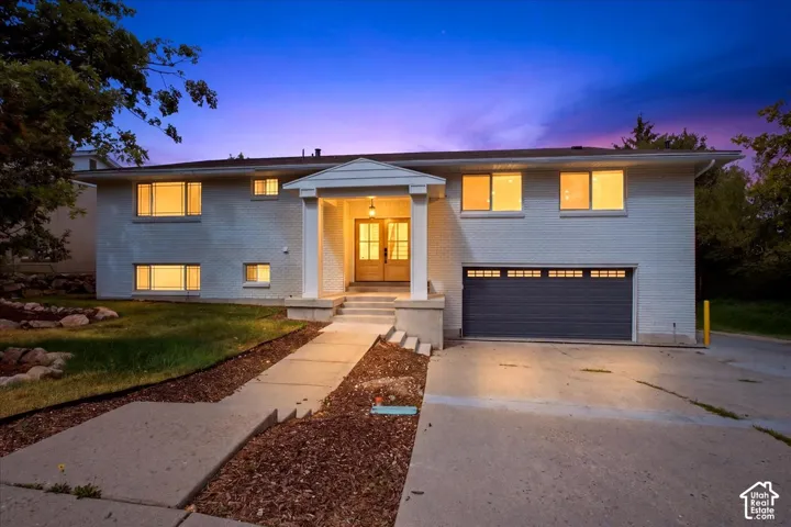 White brick exterior with a prominent front entrance, concrete walkway, attached garage with new parking pad to the north of the home for an RV or boat, and mature landscaping of course!