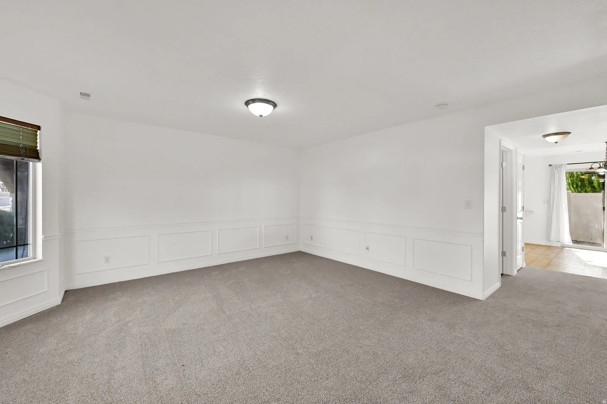 Neutral tone wall paint, carpeted flooring, wall paneling, flush mount lighting, and a bay window