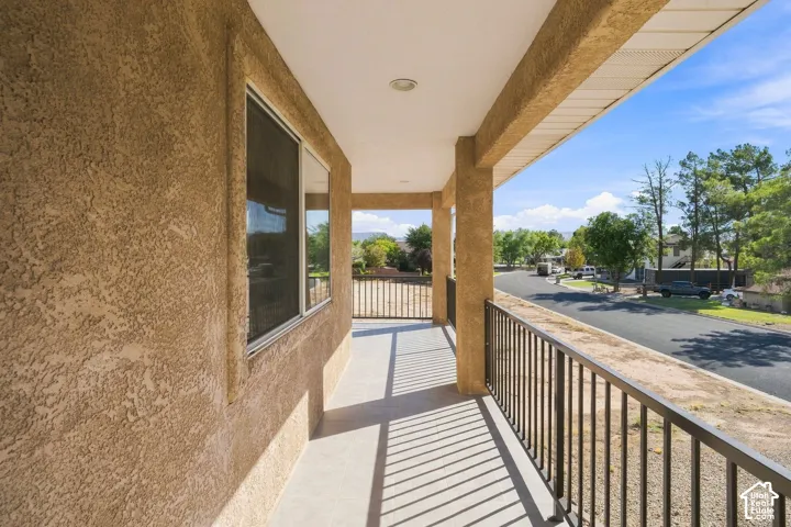Covered balcony with textured stucco finish, recessed lighting, and metal railings