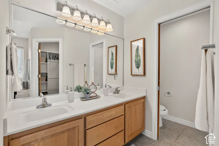 Double vanity with wood-finish cabinetry, white countertop, and integrated sinks