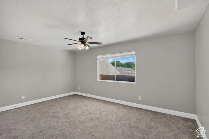 Carpeted flooring, neutral wall tones, ceiling fan with integrated lighting, and a single window